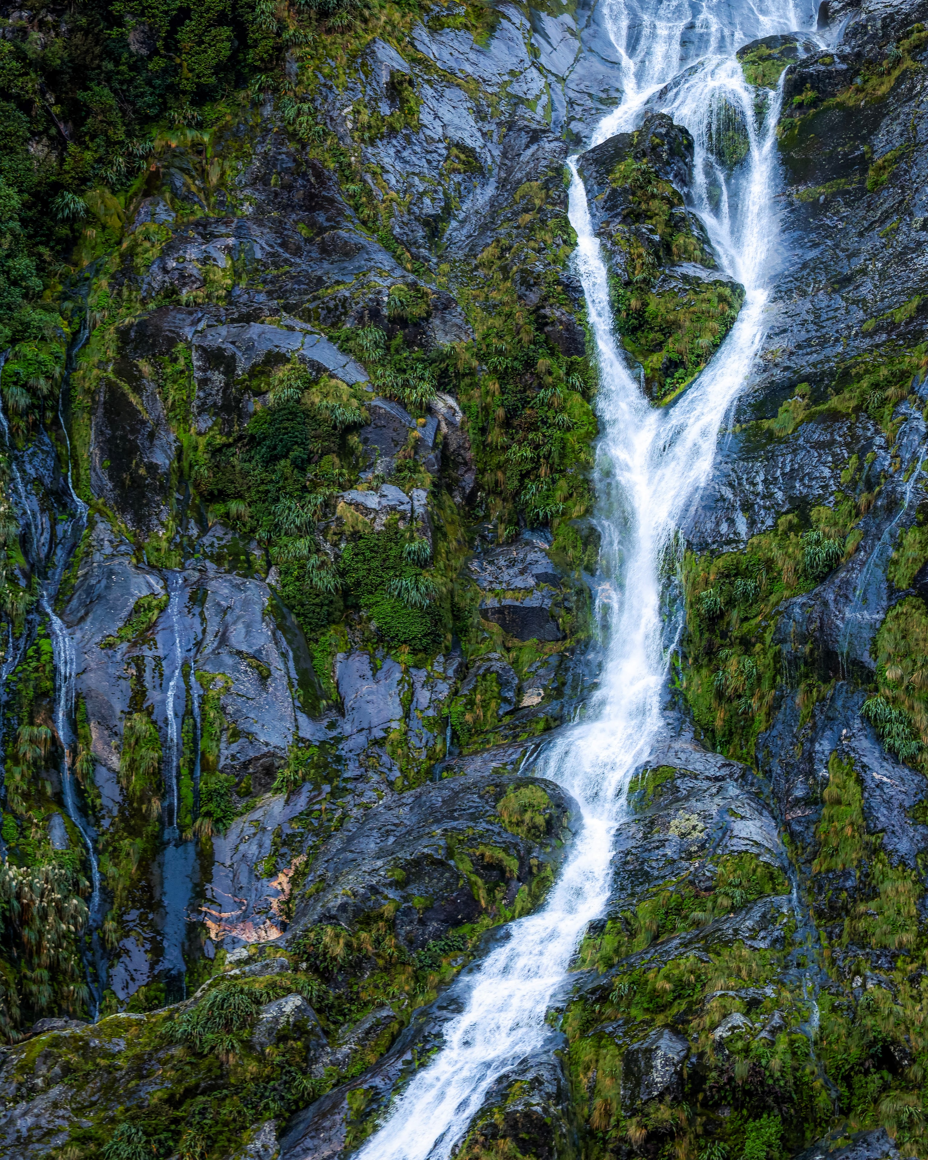 A waterfall braiding down a green cliff
